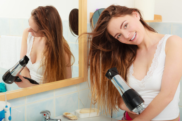 Langhaarige Frau trocknet Haare im Badezimmer - Foto, Bild