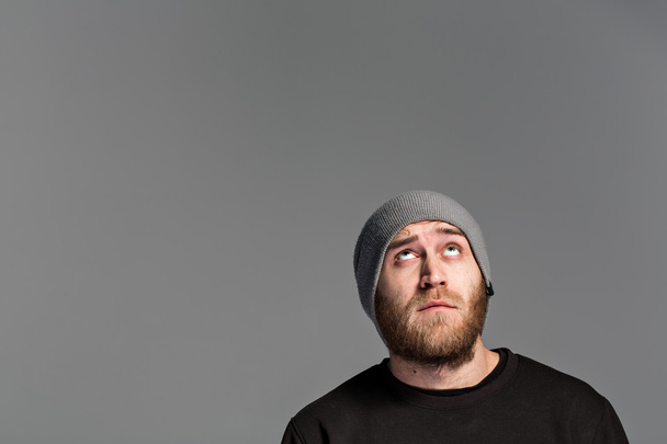 a young man with a beard wearing a hat on a gray background - 写真・画像