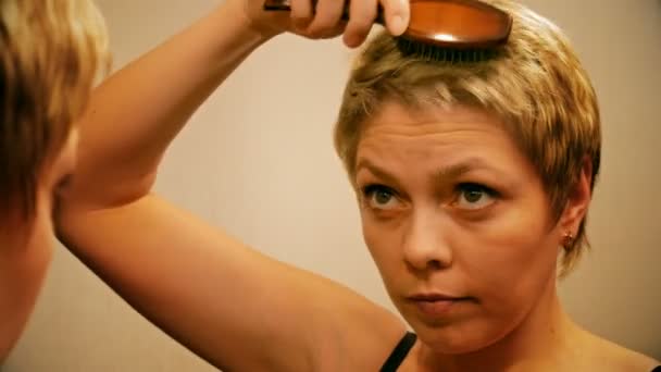 Pěkné blond žena hřebeny a kartáče na vlasy - Záběry, video