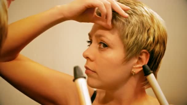 Женщина с короткими волосами вьет волосы щипцами для завивки волос
 - Кадры, видео