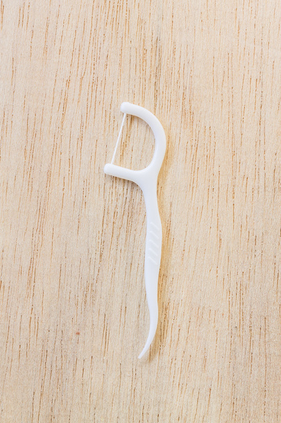 Oralgerät: eine Schachtel weißer Zahnseide auf hölzernem Hintergrund - Foto, Bild