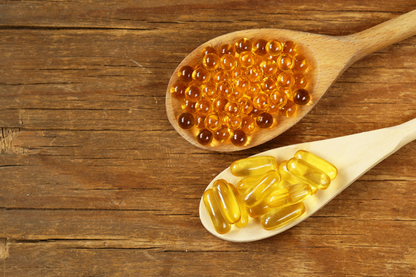 харчова добавка таблеток риб'ячого жиру в дерев'яній ложці - здорова їжа
 - Фото, зображення