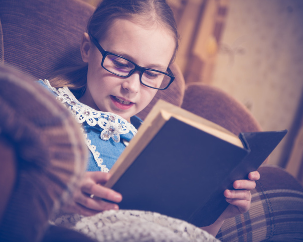 Mädchen liest zu Hause im Sessel ein Buch. - Foto, Bild
