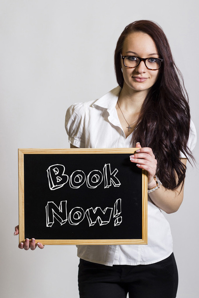 Book Now! - Young businesswoman holding chalkboard - Photo, Image
