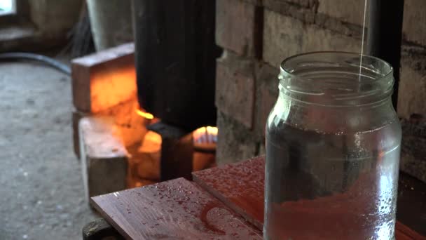 rustieke BTW-kook op brand en rogge wodka stroom in pot in de kelder. 4k - Video