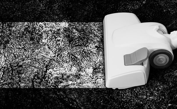 Aspiradora muy blanca sobre una alfombra muy negra
 - Foto, Imagen