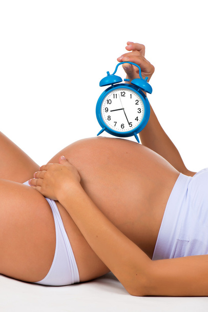 Happy pregnancy. Pregnant belly with alarm clock. Soon birth. Fetal development by months - Photo, image