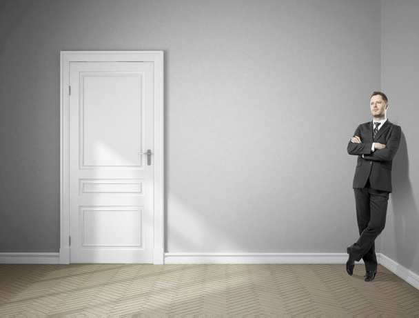 мечтающий бизнесмен, стоящий в серой комнате
 - Фото, изображение