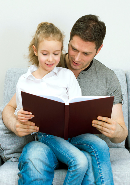 Father reading book with daughter at home. - Zdjęcie, obraz