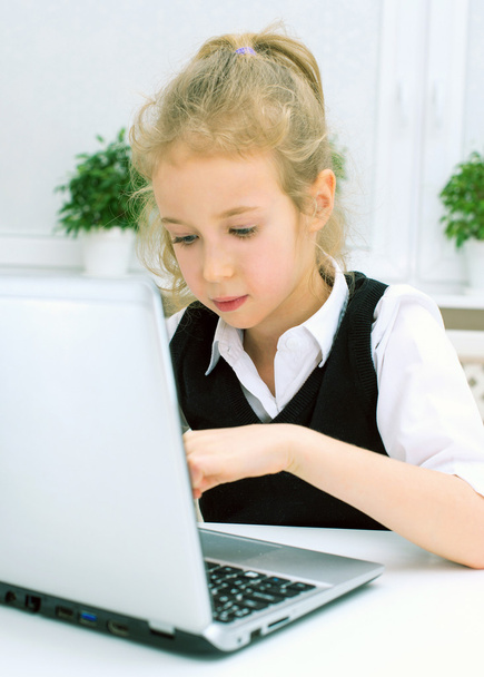 Little girl doing her homework at home, using laptop. - Foto, Imagen