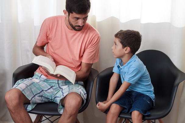 Πατέρας ανάγνωση αφηγηματικό βιβλίο στο παιδί στο σαλόνι - Φωτογραφία, εικόνα