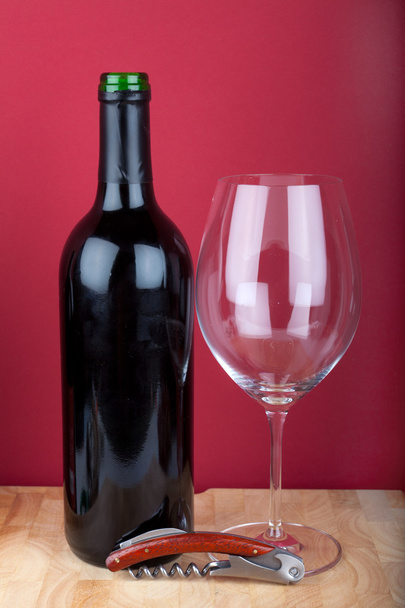 Wine bottle, glass and a corkscrew on a wooden board. - Foto, Imagen