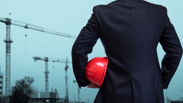 business man holding red safety helmet with construction site ba - 写真・画像