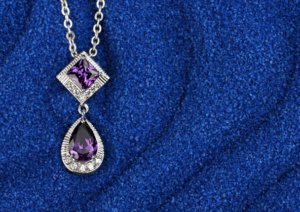 colourful Jewelry pendant with gems on dark blue sand waves back - Valokuva, kuva