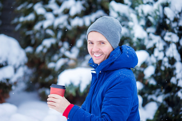 Nuori valkoihoinen mies juo kahvia kylmänä talvipäivänä ulkona
 - Valokuva, kuva