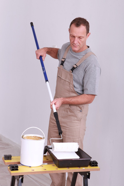 Homem aplicando tinta ao rolo
 - Foto, Imagem