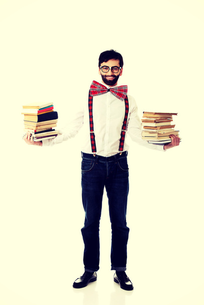 Man wearing suspenders with stack of books. - 写真・画像