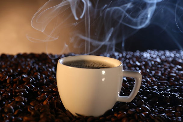 Cup of hot coffee among coffee beans on dark background - Photo, Image