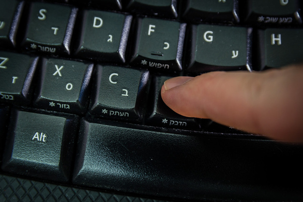 Homme tapant sur un clavier avec des lettres en hébreu et en anglais
 - Photo, image
