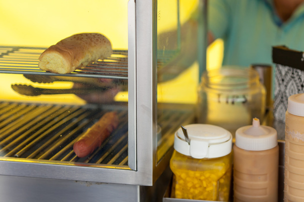 Vendedor preparando hot dog en puesto de mercado
  - Foto, imagen