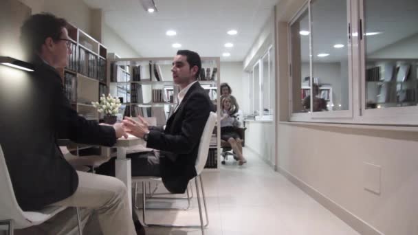 Empresários negociando enquanto as mulheres se divertem com a cadeira
 - Filmagem, Vídeo