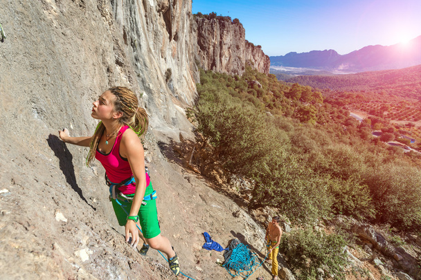 Young talented Female Rock Climber ascending rocky Wall  - Fotó, kép