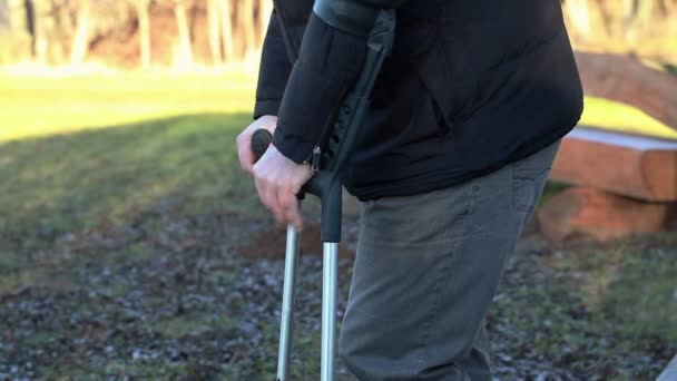 Niepełnosprawny mężczyzna o kulach na zewnątrz w pobliżu ławki - Materiał filmowy, wideo