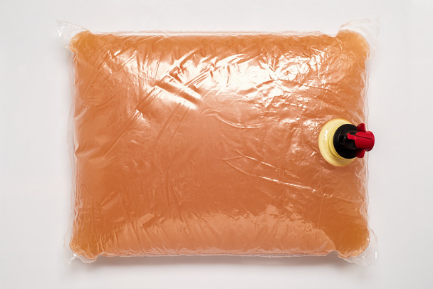 Пластиковий пакет з краном, повним яблучного соку
 - Фото, зображення