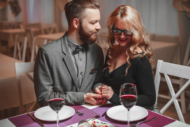 Beautiful young couple with glasses of red wine in luxury restaurant - Foto, Imagem