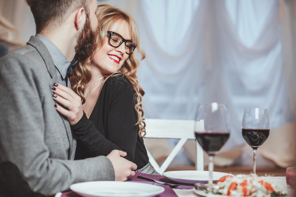 Beautiful young couple with glasses of red wine in luxury restaurant - Photo, image