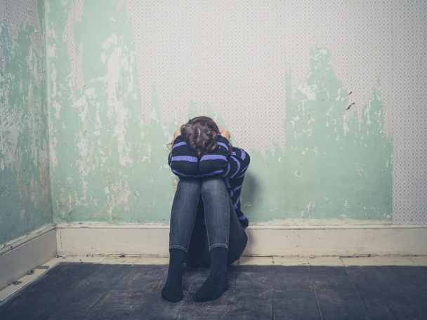Triste jovem mulher sentada no chão em quarto vazio
 - Foto, Imagem