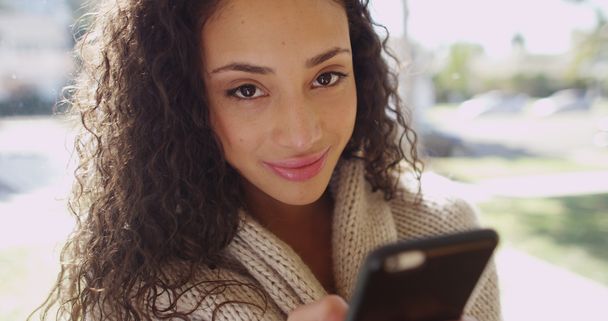 Aantrekkelijke jonge brunette op een mobiele telefoon camera glimlachen - Foto, afbeelding