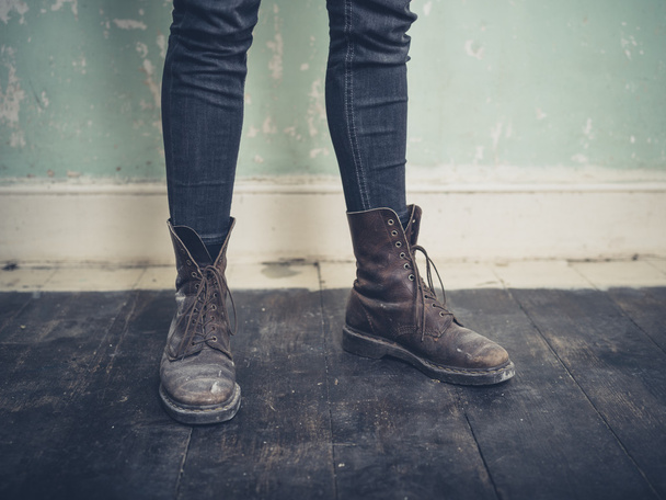 Persona que usa botas de pie en una habitación vacía
 - Foto, Imagen