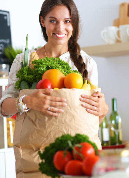 Young woman holding grocery shopping bag with vegetables - 写真・画像