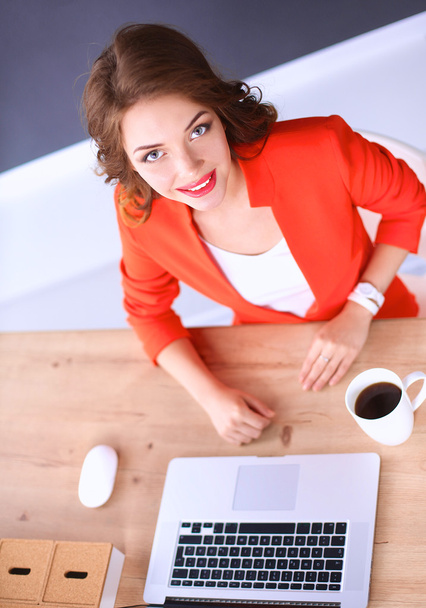 Atrakcyjna kobieta siedząca przy biurku w biurze, pracująca z laptopem - Zdjęcie, obraz