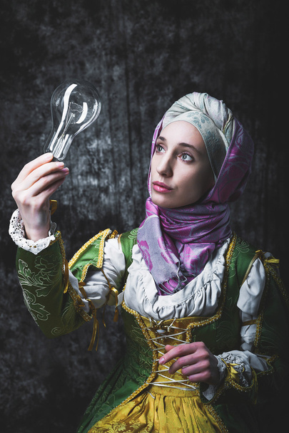 Mulher medieval segurando uma lâmpada elétrica
 - Foto, Imagem