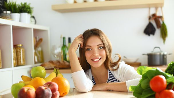 Young woman sitting near desk in the kitchen - Foto, Imagen