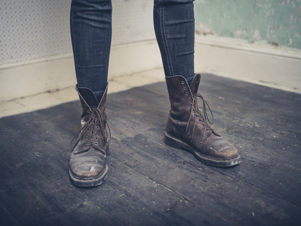Persona que usa botas de pie en una habitación vacía
 - Foto, imagen