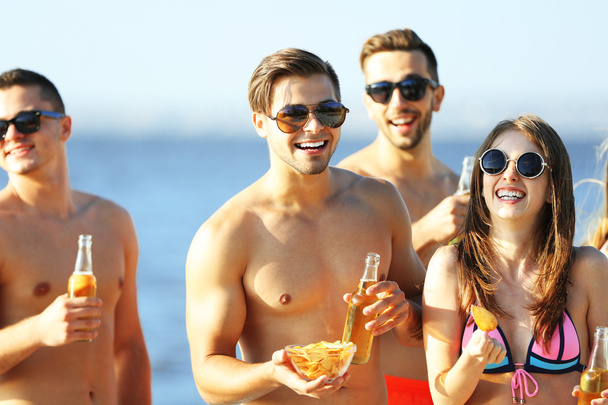 Happy friends drinking beer at beach - Foto, afbeelding