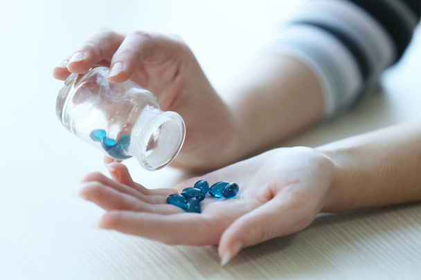 Woman spills blue medical capsules - Fotografie, Obrázek
