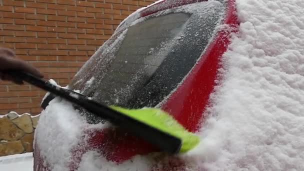 La fille nettoie la neige sur la voiture rouge. Action au ralenti
. - Séquence, vidéo