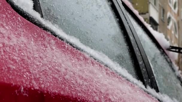 De man reinigt sneeuw op de rode auto. - Video