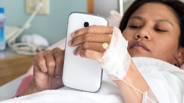 Paciente feminina em cama de hospital usando telefone
 - Foto, Imagem