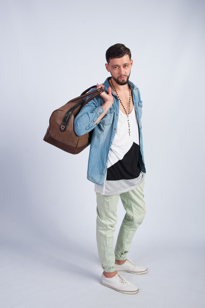 Νέος άντρας στέκεται με τσάντα ταξιδιού - Φωτογραφία, εικόνα