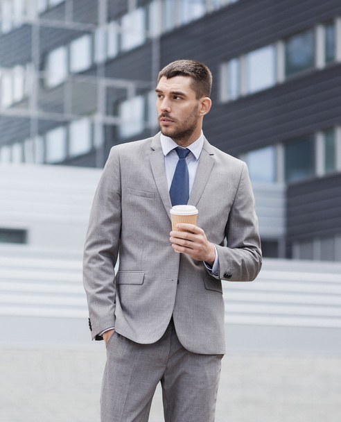 young serious businessman with paper cup outdoors - Foto, Imagen