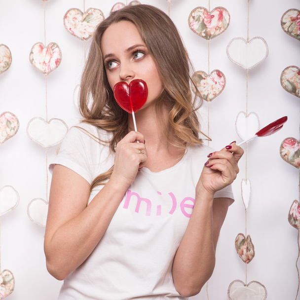 Valentines Day. Funny beautiful Woman holding candy in the form of heart - Foto, Imagen