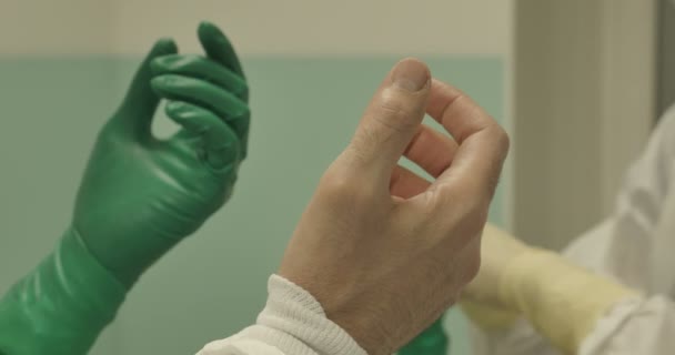 Close up hands wearing surgical gloves operating team protective clothing performing surgery using sterilized equipment - Materiał filmowy, wideo