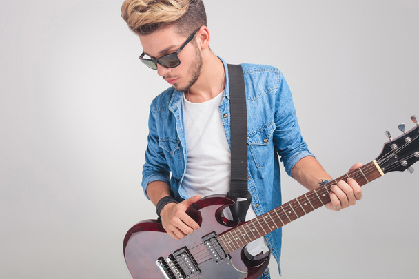 blonde man in studio wearing glasses while holding a guitar - Foto, Bild