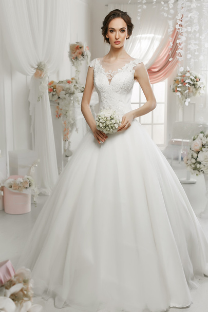 The beautiful woman posing in a wedding dress - Foto, Imagen