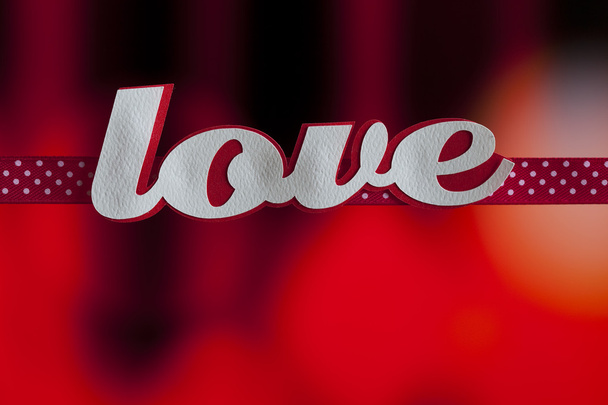 Inscription love and a red ribbon on a red background - Foto, Imagem